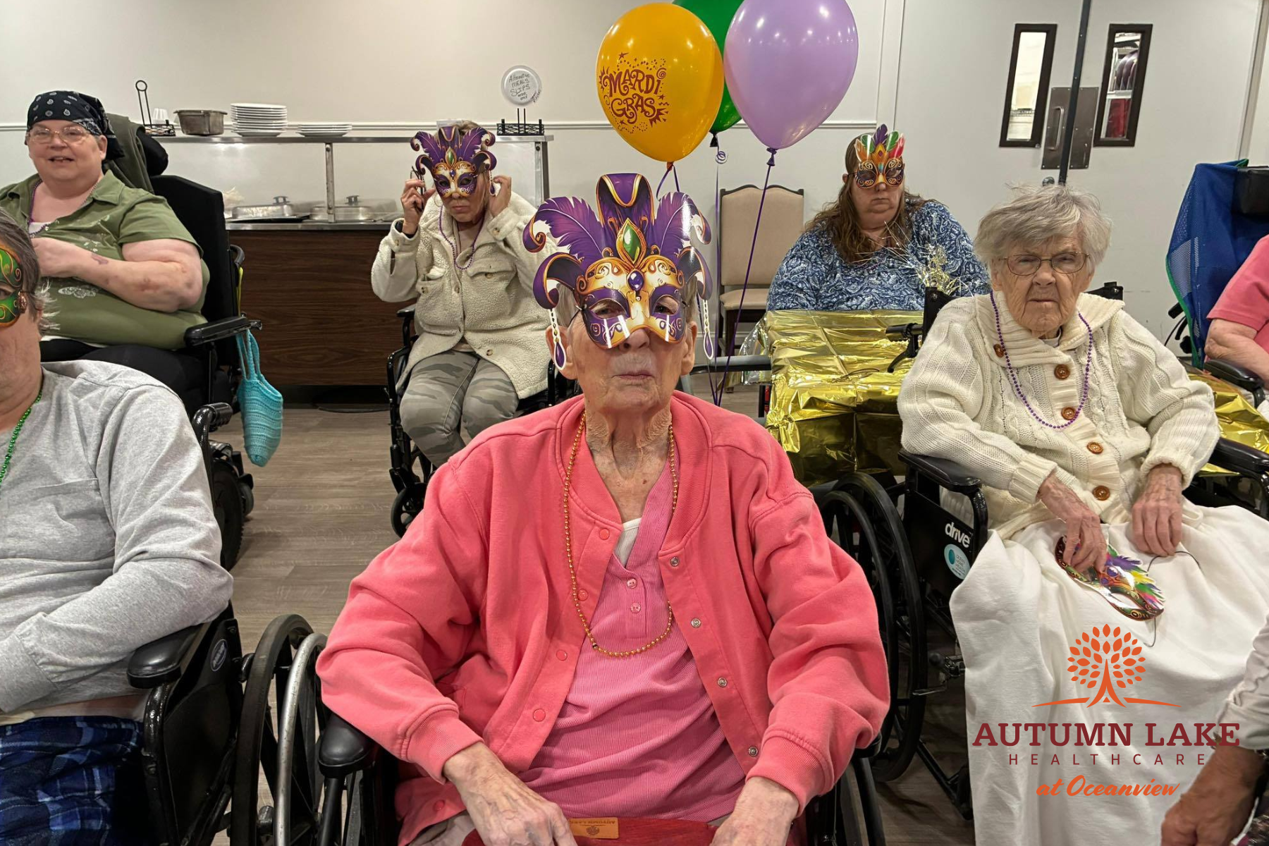 Elderly residents in wheelchairs wearing festive masks at a nursing home
